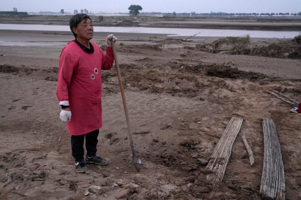 Wang Yue-tang stands near what used to be his peanut farm before torrential rains submerged the lowland leaving him with no summer harvest near Xubao village in central China’s Henan province in October 2021 (AP)