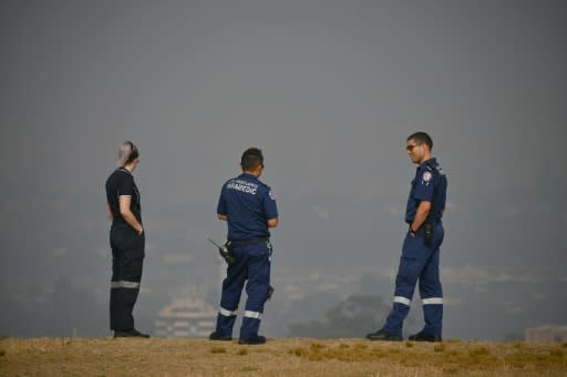 Paramedics take a break as they look out over a smokey haze which blankets Sydney