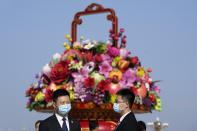 Attendees wear masks to protect from the coronavirus as they chat near a giant floral decoration setup for the Oct. 1 National Day holidays during a ceremony to mark Martyr's Day at Tiananmen Square in Beijing on Wednesday, Sept. 30, 2020. (AP Photo/Ng Han Guan)