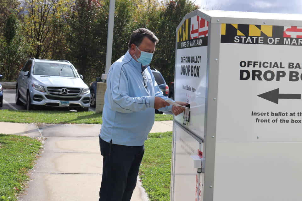 In this Oct. 30, 2020, photo, Edward Drnach, a 61-year-old Republican, drops off his wife’s ballot before he goes into a voting center in Ellicott City, Md., to vote for Democrat Joe Biden for president. Drnach said he’s tired of Republican President Donald Trump, though he’s still voting for a Republican candidate for Congress, Kimberly Klacik. (AP Photo/Brian Witte)