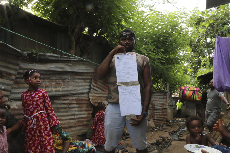 A man shows a French official document forbidding to park near the Talus 2 district of Koungou, in the French Indian Ocean territory of Mayotte, Saturday, April 22, 2023. France is facing a migration quagmire on the island territory of Mayotte off Africa’s east coast. The government sent in 2,000 troops and police to carry out mass expulsions, destroy slums and eradicate violent gangs. But the operation has become bogged down and raised concerns of abuse, aggravating tensions between local residents and immigrants from the neighboring country of Comoros. (AP Photo/Gregoire Merot)