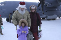 Santa and Mrs. Claus pose with a child who braved winds chills off about minus 25 degrees to greet them when they landed Tuesday, Nov. 29, 2022, in Nuiqust, Alaska. Operation Santa Claus, the Alaska National Guard's outreach program, attempts to bring Santa and Mrs. Claus and gifts to children in two or three Alaska Native villages each year, including Nuiqsut in 2022. (AP Photo/Mark Thiessen)