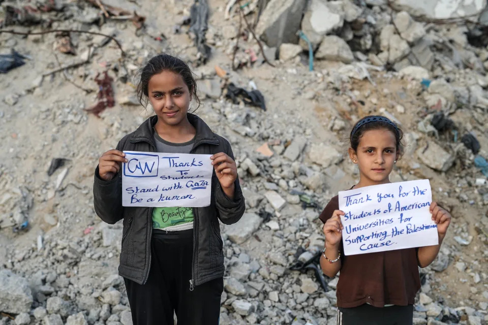 <p>La imagen de Rafah muestra a dos niñas sosteniendo pancartas con mensajes de agradecimiento mientras advertían que violar su derecho a la vida y la educación era un crimen de guerra. "Gracias a los estudiantes de EEUU por apoyar la causa palestina"/Los campamentos de los estudiantes en Estados Unidos y Canadá han sido tan visibles, que han obligado a la ciudadanía a prestar atención tanto a las demandas de los manifestantes como a la situación en Gaza, donde el tribunal superior de las Naciones Unidas ha dicho que los palestinos enfrentan un riesgo de genocidio. (Photo by Jehad Alshrafi/Anadolu via Getty Images)</p> 