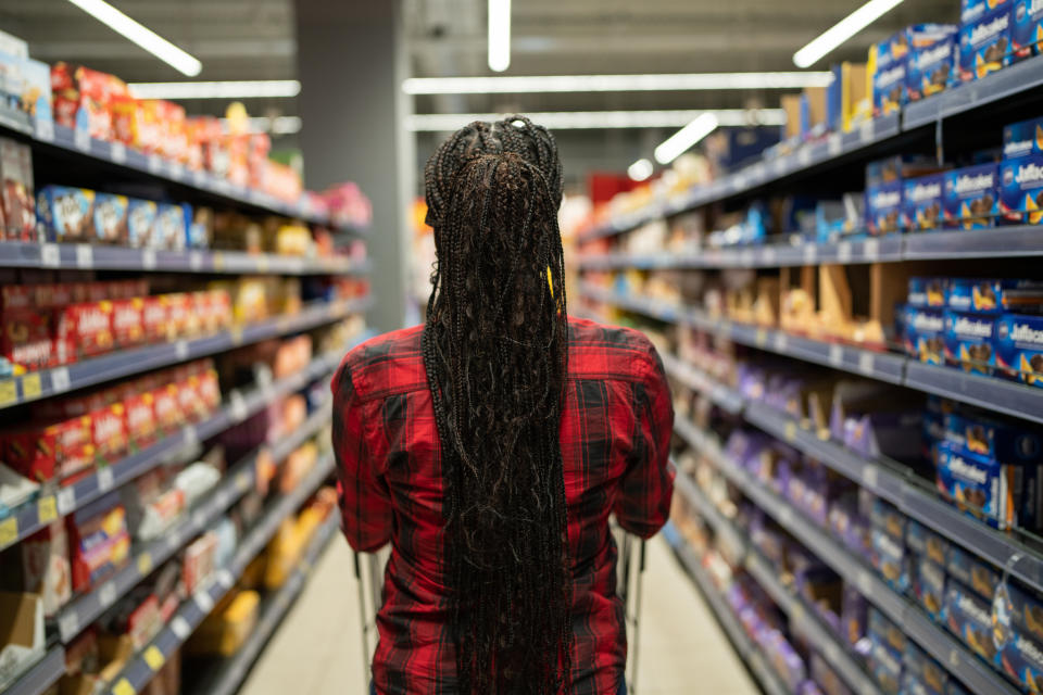 Unrecognizable black woman pushing shopping cart at the supermarket.