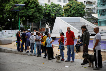 People line up as other charge their phones with a solar panel at a public square in Caracas, Venezuela March 10, 2019. REUTERS/Carlos Garcia Rawlins