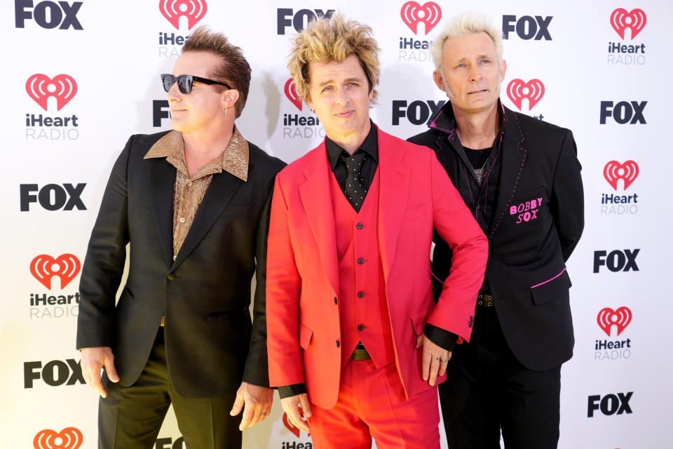 Tre Cool, Billie Joe Armstrong in a bright suit, and Mike Dirnt on the red carpet at iHeartRadio event