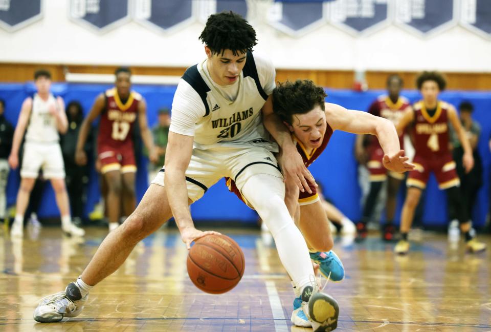 Archbishop Williams Josh Campbell keeps the ball away from Cardinal Spellman defedner Matt O'Donnell during a game at  Scituate High School on Wednesday, March 15, 2023.  