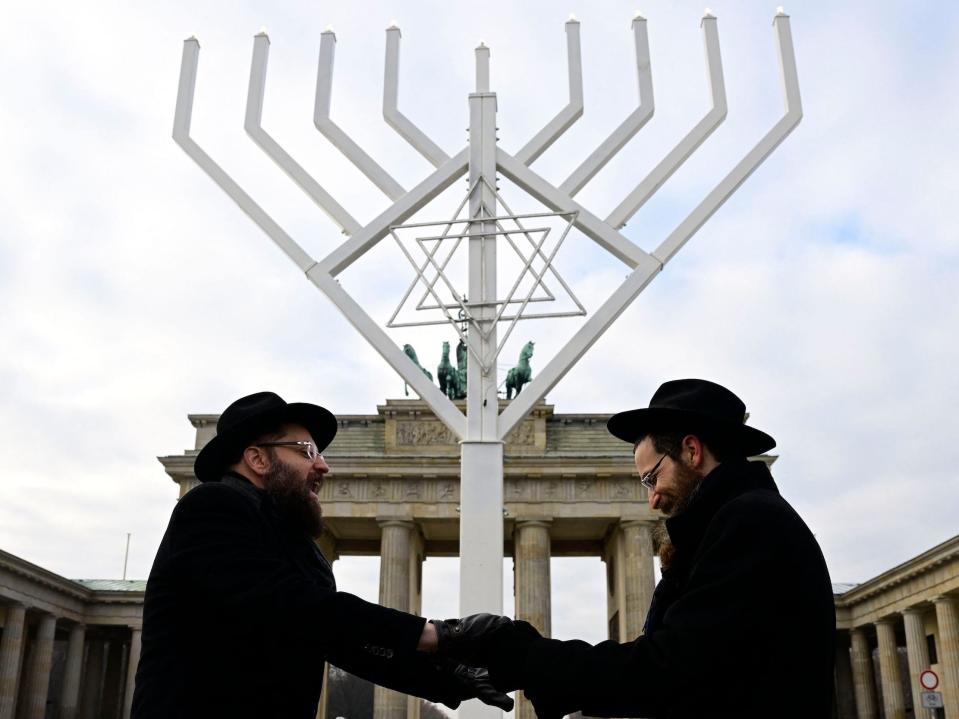 Rabbis Yehuda Teichtal (L) and Shmuel Segal sing and dance as they consecrate a giant menorah in front of the Brandenburg Gate