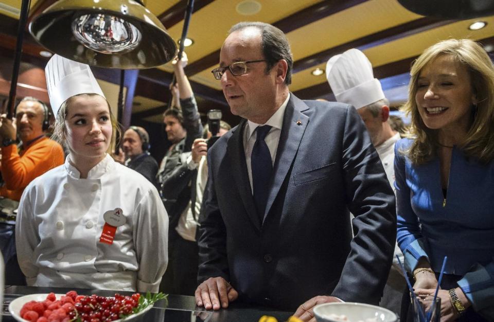 French President Francois Hollande, center, and Catherine Powell, right, president of Euro Disney watch apprentice cooks working as they attend a ceremony to mark the 25th anniversary of Disney Land in Marne-la-Vallee, north of Paris, Saturday Feb. 25, 2017. Hollande visited Disneyland Paris as Europe's most popular tourist attraction struggles with long-running financial challenges. (Christophe Petit Tesson/Pool photo via AP)