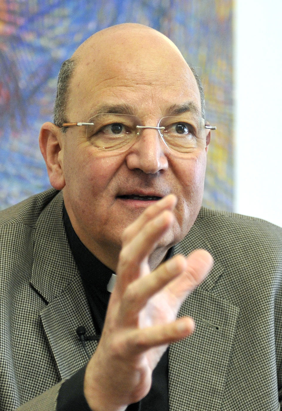 In this photo taken Tuesday, Jan. 21, 2014, church provost Christian Leibnitz speaks during an interview with the Associated Press on Nazi symbols on gravestones at a cemetary in Graz, Austria. Austrian law bans such symbols, and those displaying them face criminal charges and potential prison terms. Yet the emblems reflecting this country’s darkest chapter in history endure here, and officials here appear either unable or unwilling to do away with them. (AP Photo/Hans Punz)