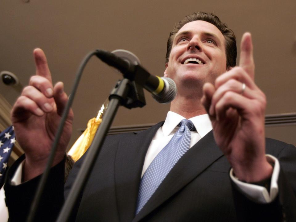 San Francisco Mayor Gavin Newsom gestures while speaking into a microphone during a media conference.
