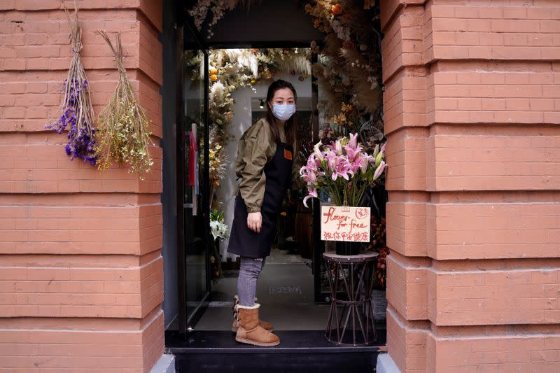 Florist Wang Haiyan, 41, stands at an entrance to her shop as the country is hit by an outbreak of the new coronavirus, in Shanghai
