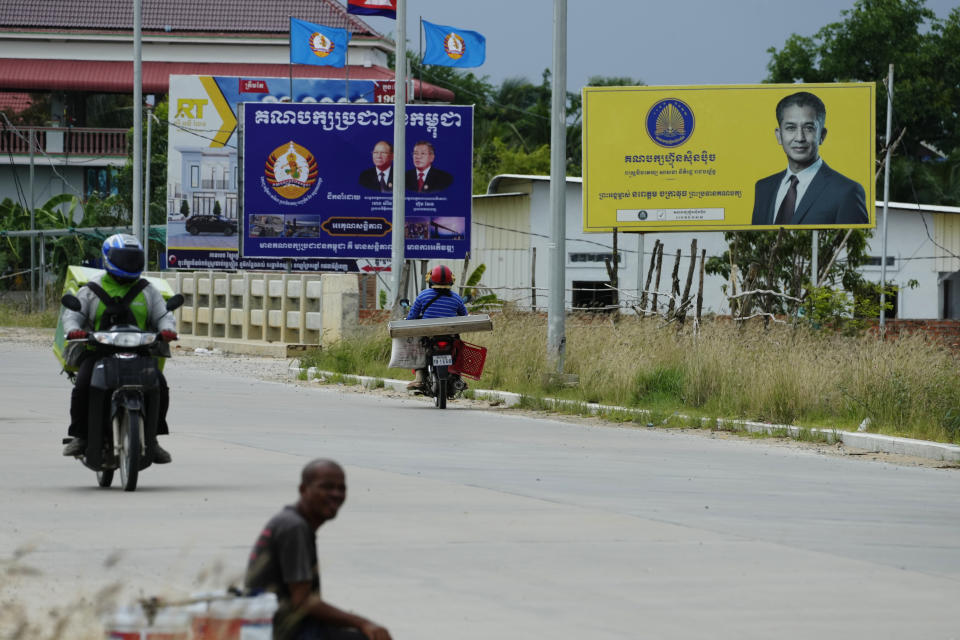 A Cambodian beggar sits on the sidewalk near political party posters including the National United Front for an Independent, Neutral, Peaceful and Cooperative Cambodia party (FUNCINPEC), upper right, and Cambodia People's Party (CPP), upper left, during a campaign rally period for the July 23 general election on the outskirts of Phnom Penh, Cambodia, Thursday, July 20, 2023. (AP Photo/Heng Sinith)