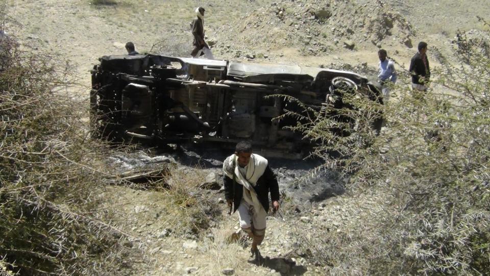 People inspect the wreckage of a car hit by an air strike in the central Yemeni province of al-Bayda April 19, 2014. The air strike killed 13 suspected al Qaeda militants in the central Yemeni province of al-Bayda on Saturday, security and tribal sources said. REUTERS/Stringer (YEMEN - Tags: POLITICS CIVIL UNREST)