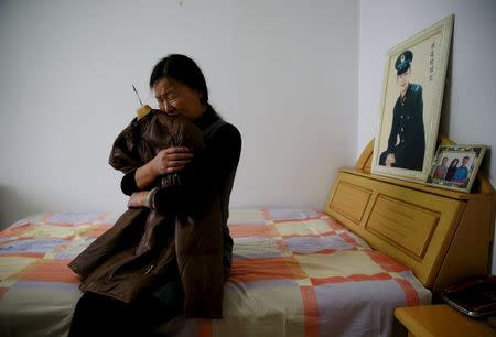 Zheng Qing hugs her dead son's favourite jacket as she shows it to reporters during an interview at her house in Zhangjiakou, China, November 22, 2015. REUTERS/Kim Kyung-Hoon