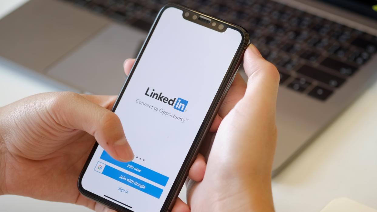  Hand holding phone with LInkedIn app. 