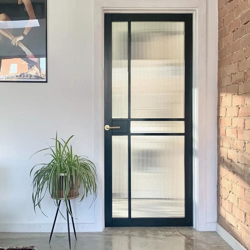 View of a black-framed glass door with reeded glass window film applied to the pane