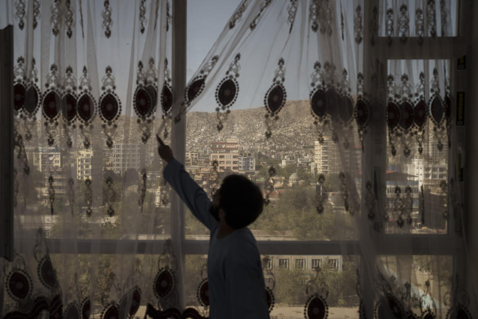Mohammed Zakir closes the curtains of his family home, overlooking Kabul, Afghanistan, Friday, Sept. 17, 2021. Zakir's bother, Zaki Anwari, was a 17-year-old soccer player who died after trying to board a departing U.S. Air Force aircraft last month. (AP Photo/Felipe Dana)