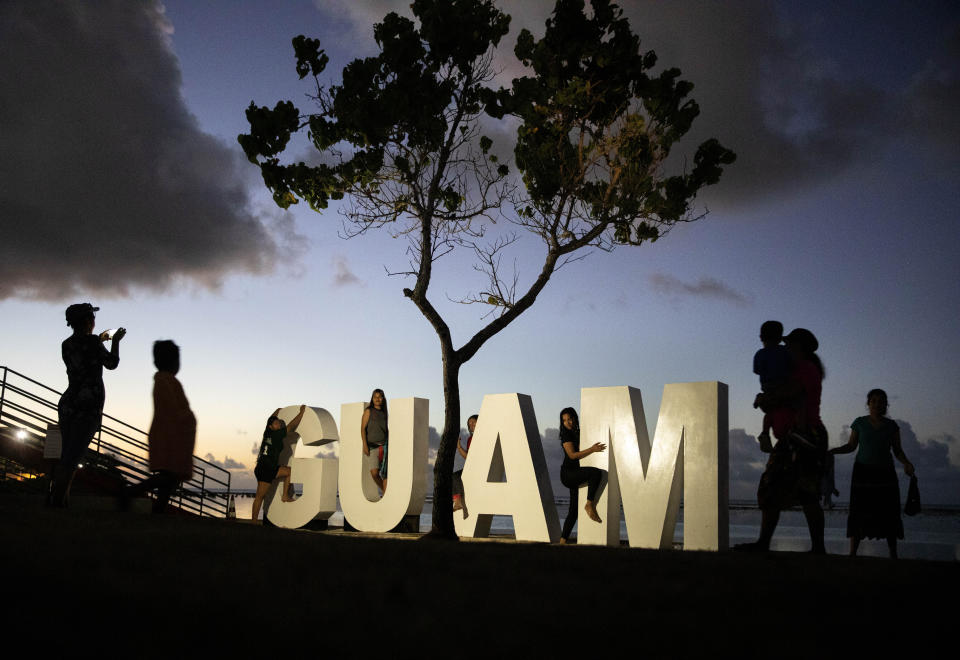 CAPTION CORRECTION CORRECTS DATE: FILE - Tourists pose for photos at a sign along a popular beach in Tamuning, Guam, May 11, 2019. The powerful Pacific typhoon Mawar that lashed of Guam on Thursday, May 25, 2023, with damaging high winds, heavy rains and a dangerous storm surge arrived as the worst storm in decades, interrupting life for residents and the U.S. military on a tropical island that is the easternmost of the nation's territories. (AP Photo/David Goldman, File)