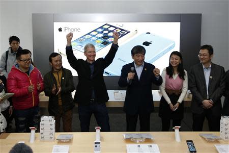 Apple Inc.'s CEO Tim Cook (3rd L) reacts next to China Mobile Ltd's Chairman Xi Guohua (3rd R) at an event celebrating the launch of Apple's iPhone on China Mobile's network at a China Mobile shop in Beijing January 17, 2014. REUTERS/Kim Kyung-Hoon