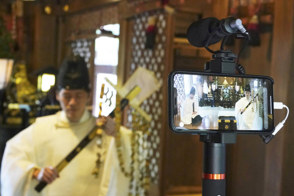 In this May 8, 2020, photo, Ryoki Ono, head priest, performs a livestream prayer during a 10-day trial of "online shrine" visit program at Onoterusaki Shrine in downtown Tokyo, allowing its visitors to join rituals from their homes. The shrine also accepted from worshipers their prayer messages, which were printed on a virtual wooden tablet each and offered to the Shinto gods to keep away evil spirits and the epidemic. (AP Photo/Eugene Hoshiko)