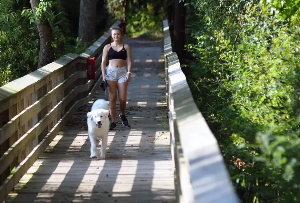 Samantha McDonald walks her dog Ava at the Brunswick Riverwalk at Belville in Bellville, N.C., Saturday, July 24, 2021.