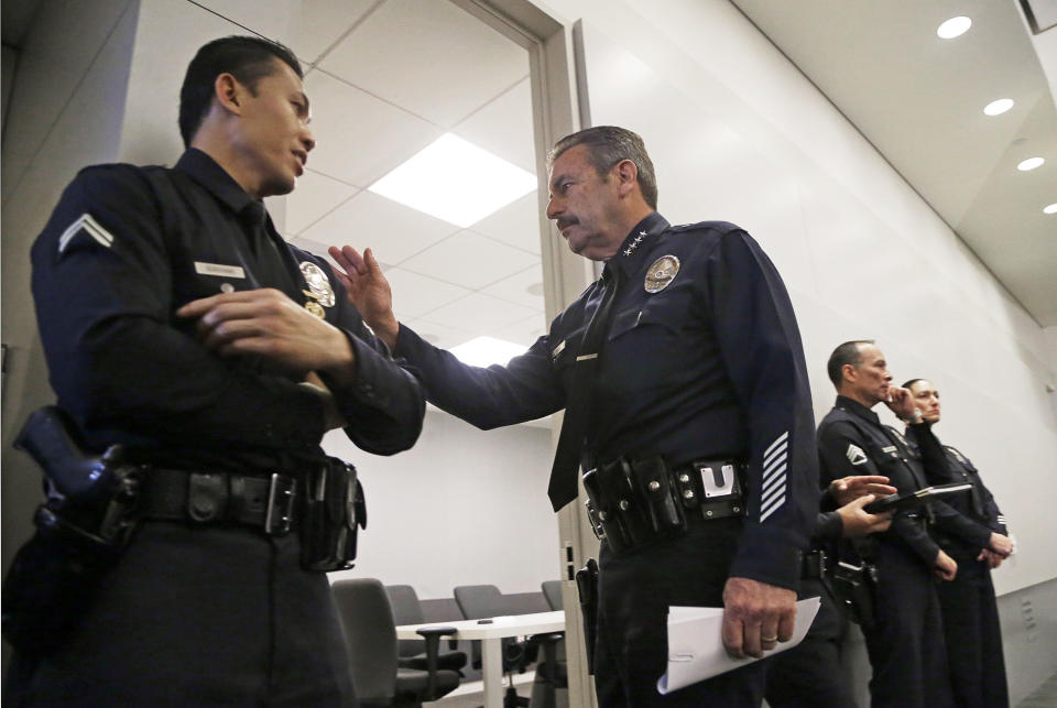 Los Angeles Police Chief Charlie Beck, center, touches Officer Bruce Borihanh after a news conference at LAPD headquarters in downtown Los Angeles Tuesday, Feb. 4, 2014. A civilian oversight board has determined that eight Los Angeles police officers violated department policy when they mistakenly opened fire on two women during the manhunt for rogue ex-cop Christopher Dorner. The Police Commission's decision announced Tuesday leaves the question of disciplinary measures to Beck. The officers have been assigned to non-field duties pending the internal investigation. (AP Photo/Reed Saxon)