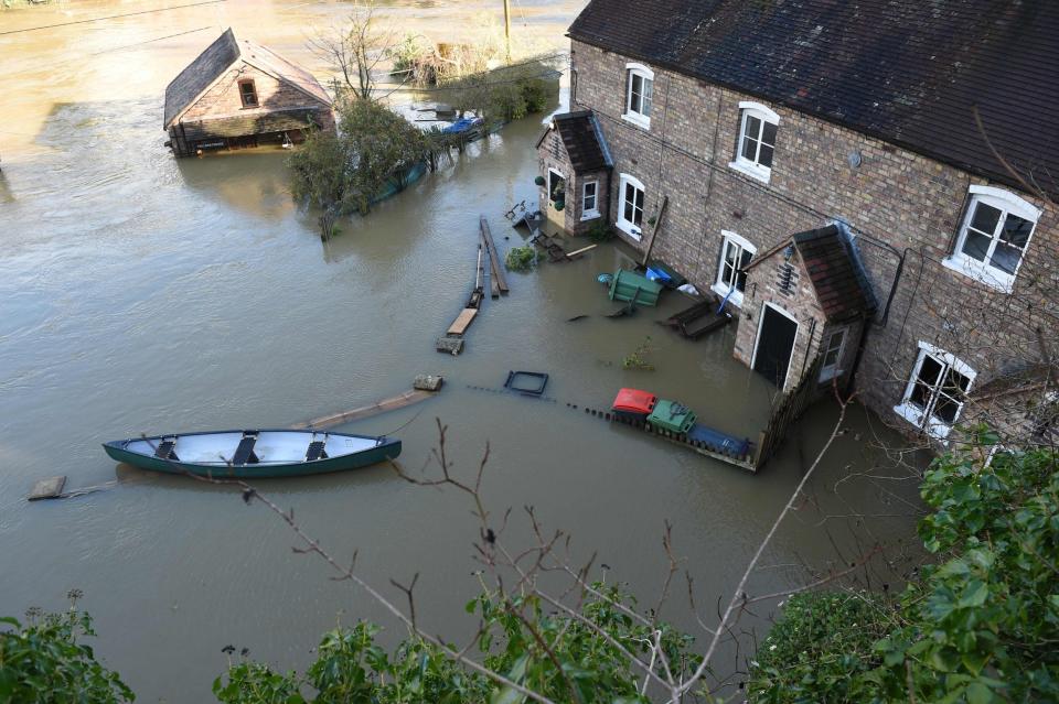 A picture shows a canoe outside a flooded home in Ironbridge (AFP via Getty Images)