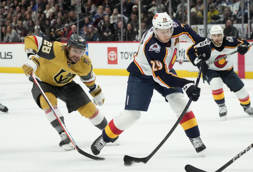 Colorado Avalanche center Nathan MacKinnon, right, shoots the puck after driving past Vegas Golden Knights left wing William Carrier in the third period of an NHL hockey game, Monday, Jan. 2, 2023, in Denver. (AP Photo/David Zalubowski)