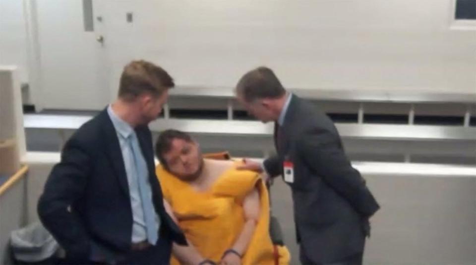 Anderson Lee Aldrich, 22, the suspect in the mass shooting that killed five people and wounded 17 at an LGBTQ nightclub appears with state public defenders Joseph Archambault and Michael Bowman before a judge during their advisement hearing in a video link from jail, slumped to the side and in a wheelchair and showing facial injuries in a still image from video in Colorado Springs, Colorado (via REUTERS)