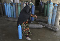 A woman carries an oxygen cylinder from a privately owned oxygen factory, in Kabul, Afghanistan, Saturday, June 19, 2021. Health officials say Afghanistan is fast running out of oxygen as a deadly third surge of COVID worsen. (AP Photo/Rahmat Gul)