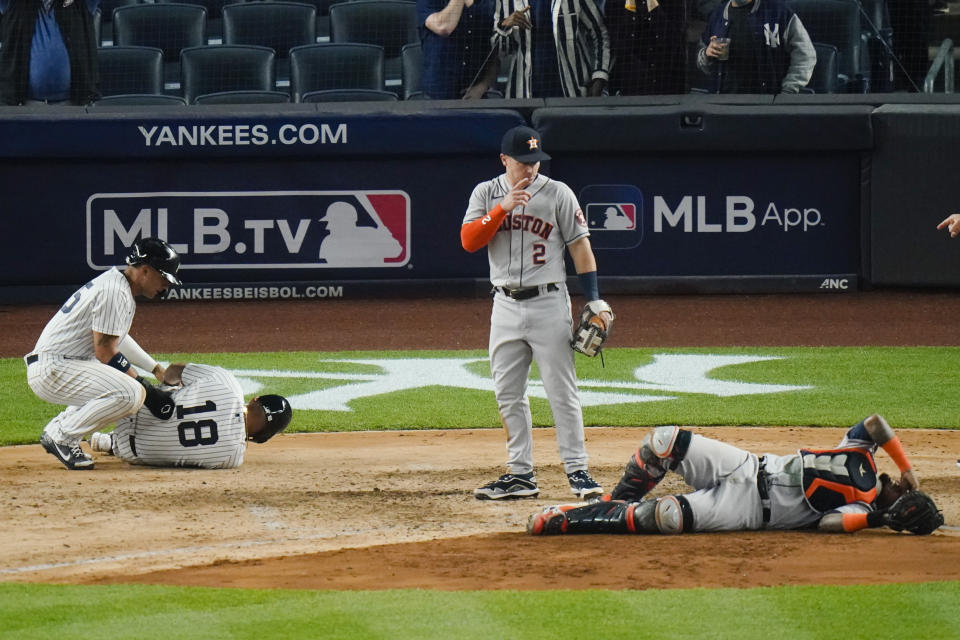 Houston Astros' Alex Bregman, center, watches as New York Yankees' Rougned Odor, left, and Houston Astros catcher Martin Maldonado, right, react to being injured on a play at home plate during the sixth inning of a baseball game Tuesday, May 4, 2021, in New York. (AP Photo/Frank Franklin II)