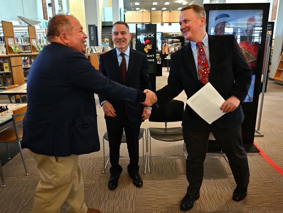 Dr. Charles Steinberg, left, president of the Worcester Red Sox, shakes hands with Tim Murray, president and CEO of the Worcester Regional Chamber of Commerce, as National Baseball Poetry Festival organizer Steven Biondolillo looks on before Monday's press conference at the Worcester Public Library on Salem Street.