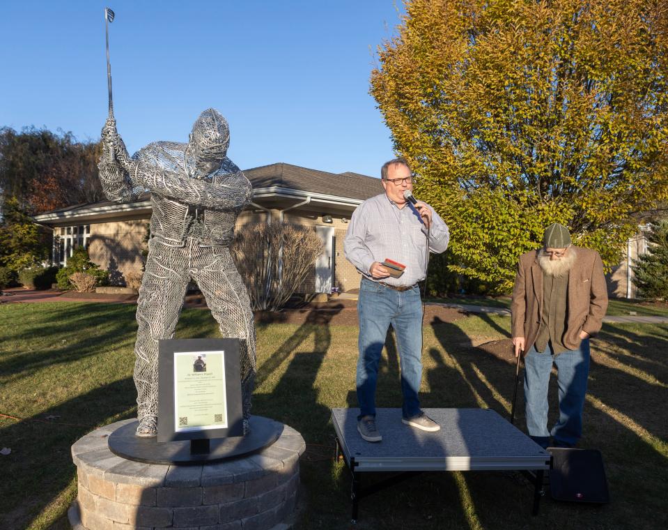 Bob Clark of the Minerva Arts Council addresses the crowd at the dedication of the William J. Powell statue outside the Minerva Public Library.To his right is the statue's artist, Patrick Buckohr.