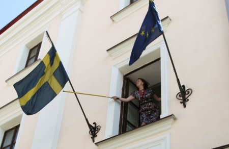FILE PHOTO: An employee rearranges the national flag of Sweden at the Swedish embassy in Minsk August 8, 2012. REUTERS/Vasily Fedosenko/File Photo
