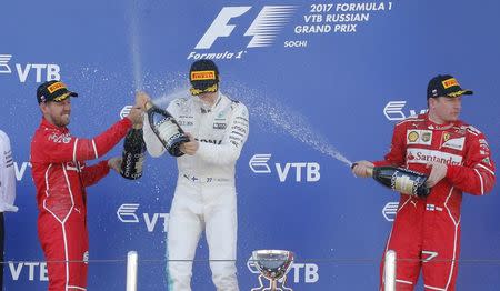 Formula One - F1 - Russian Grand Prix - Sochi, Russia - 30/04/17 - Winner and Mercedes Formula One driver Valtteri Bottas (C) of Finland, second-placed Ferrari Formula One driver Sebastian Vettel (L) of Germany and third-placed Ferrari Formula One driver Kimi Raikkonen of Finland spray champagne on the podium on the podium. REUTERS/Maxim Shemetov