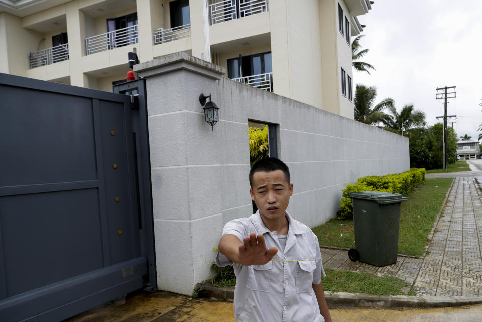 In this Monday, April 8, photo, a Chinese Embassy staff member gestures to stop taking photos outside the embassy accommodation building in Nuku'alofa, Tonga. China is pouring billions of dollars in aid and low-interest loans into the South Pacific, and even in the far-flung kingdom of Tonga there are signs that a battle for power and influence among much larger nations is heating up and could exact a toll. (AP Photo/Mark Baker)