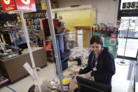 In this photo taken Wednesday, March 25, 2020, hardware clerk Rebecca Peil, right, works behind a plexiglass barrier built a few days earlier by a co-worker to help protect employees and customers during the coronavirus outbreak, in Seattle. The store is expected to remain open under Gov. Jay Inslee's stay-at-home order issued Monday in the midst of the coronavirus outbreak, with only "essential" service providers allowed to go to their jobs. (AP Photo/Elaine Thompson)