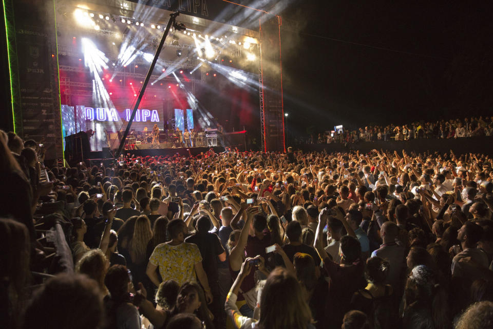 FILE - Fans cheer as British-Kosovar singer Dua Lipa performs on stage during her first concert held in Kosovo's capital Pristina, at the Germia Park on August 9, 2016. While Albania’s capital Tirana is bristling with preparations for holding an international music festival, its neighboring Kosovo’s counterpart Pristina is swarmed into political confrontations after losing it. The Sunny Hill Festival will be held this year Aug. 4-7 in Tirana instead of Pristina following a political controversy between Kosovo’s leftwing Self Determination Movement!-led government and opposition Democratic League of Kosovo running the capital. (AP Photo/Visar Kryeziu, File)