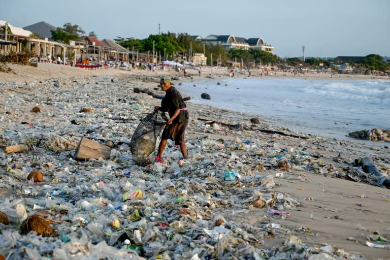 Un homme ramasse des objets recyclables pour les vendre au milieu de plastiques et d'autres débris échoués sur la plage de Kedonganan, dans la zone touristique de Kuta, sur l'île de Bali, en Indonésie, le 19 mars 2024 (SONNY TUMBELAKA)