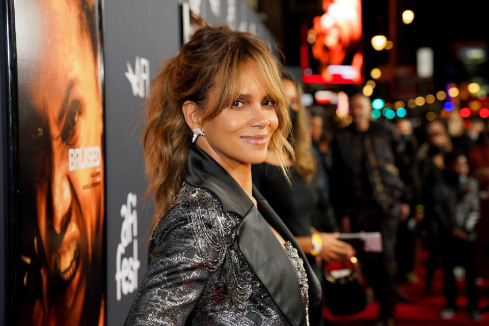 Halle Berry smiles for the camera on the red carpet in a sparkly jacket
