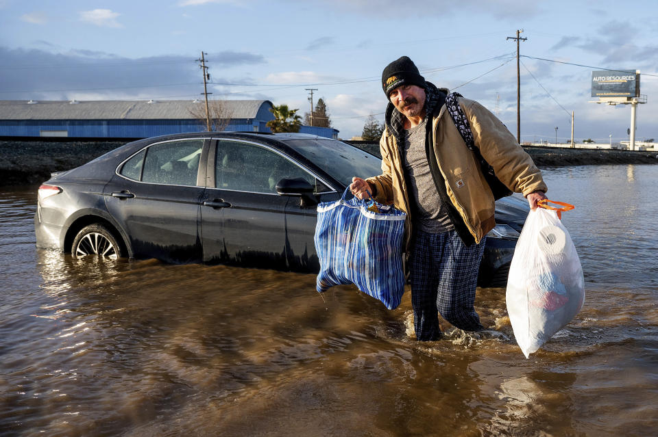 Jesús Torres saca pertenencias de su casa inundada por las lluvias en Merced, California, el martes 10 de enero de 2023. (AP Foto/Noah Berger)