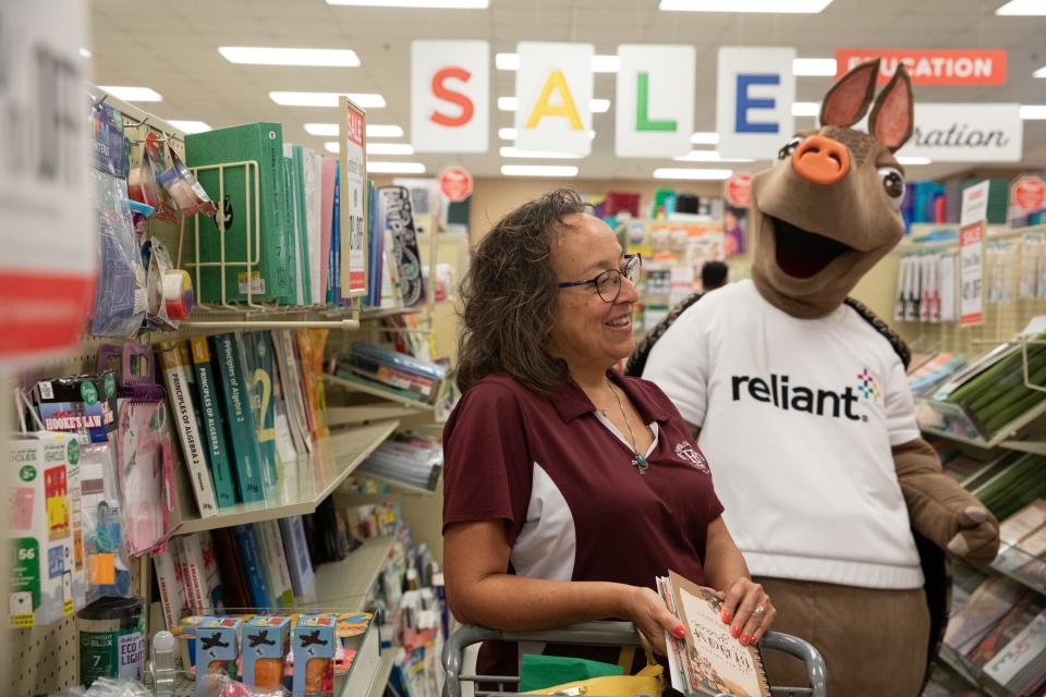 Flour Bluff Intermediate School STEAM teacher Ada Anderson looks through school supplies while Reliant mascot Hugo watches during a sponsored shopping trip to the Mardel Christian and Education store on Thursday in Corpus Christi.