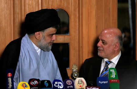 Iraqi Shi'ite cleric Moqtada al-Sadr, who's bloc came first, looks at Iraqi Prime Minister Haider al-Abadi, who's political bloc came third in a May parliamentary election, during a news conference in Najaf, Iraq June 23, 2018. REUTERS/Alaa al-Marjani