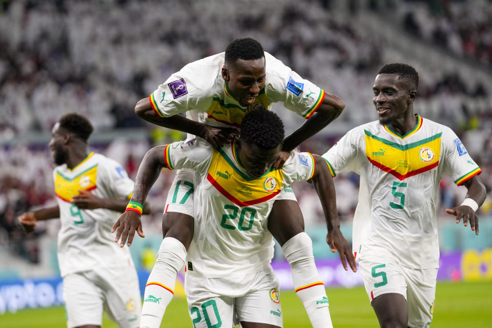 Temmates celebrate with Senegal's Bamba Dieng after he score their third goal against Qatar during a World Cup group A soccer match at the Al Thumama Stadium in Doha, Qatar, Friday, Nov. 25, 2022. (AP Photo/Petr Josek)