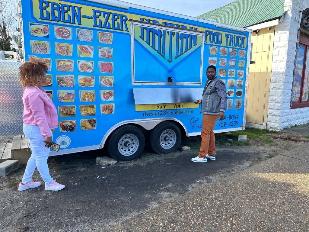 Clemene Bastien and Theslet Benoir stand outside of their Eben-Ezer Haitian food truck in Parksley, Va., on Wednesday, Jan. 24, 2024. The married couple is suing the town in federal court over allegations that their food truck was forced to close. The couple also says a town councilman cut the mobile kitchen’s water line and screamed, “Go back to your own country!” (AP Photo/Ben Finley)