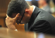 Oscar Pistorius holds his head in his hands as he listens to evidence being given in court in Pretoria, South Africa, Monday March 24, 2014. Pistorius is on trial for the shooting death of his girlfriend Steenkamp on Valentine's Day 2013. (AP Photo/Ihsaan Haffejee, Pool)