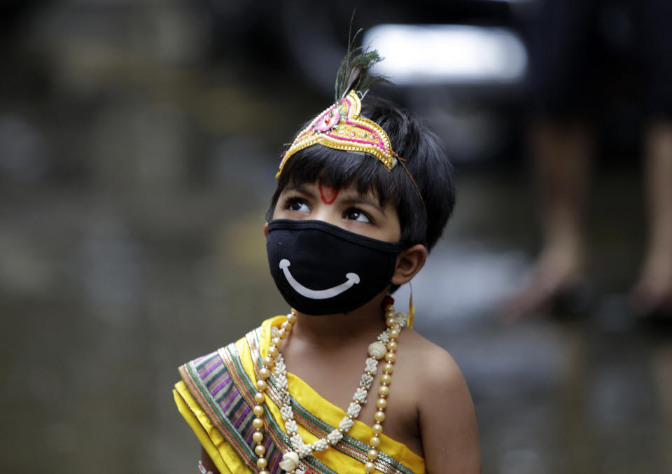 A boy dressed as Hindu god Krishna wears a mask as a precaution against the coronavirus during Janmashtami festival celebrations in Mumbai, India, Wednesday, Aug.12, 2020. The festival marks the birth anniversary of Krishna. (AP Photo/Rajanish Kakade)