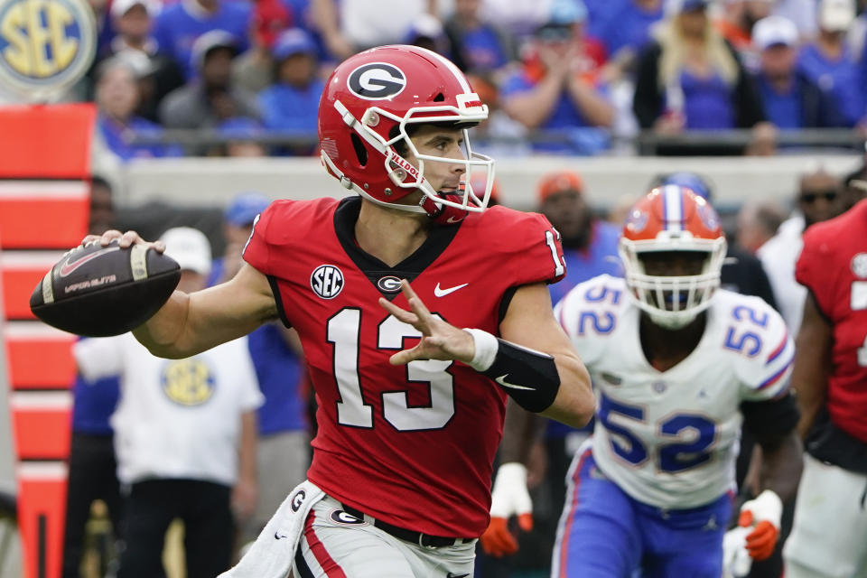 Georgia quarterback Stetson Bennett (13) looks for a receiver as Florida linebacker Antwaun Powell-Ryland Jr. (52) rushes during the first half of an NCAA college football game Saturday, Oct. 29, 2022, in Jacksonville, Fla. (AP Photo/John Raoux)