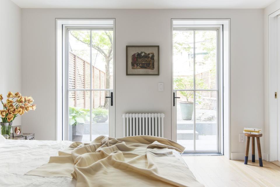 The steel and glass doors in the serene downstairs master bedroom are a simpler version of the ones on the parlor level. "They have that really thin profile to give you as much glass as possible," says Roberts. Save for the door handles, all of the hardware matches the metal exactly. "It goes along with the minimalist, light, white feel."